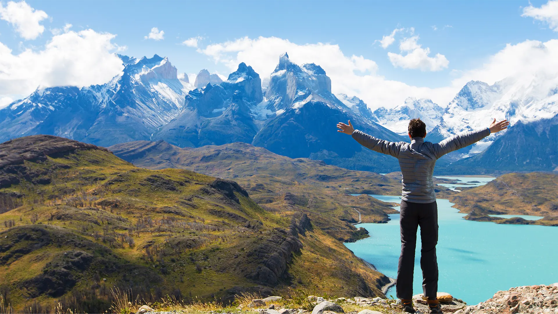 hombre de espaldas de brazos abiertos en la sima de una montaña viendo el paisaje